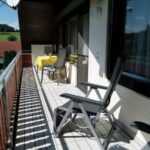 Balkon zur Südseite mit Tisch und Stühlen sowie Relaxliegen, zur Beschattung gibt es eine Markise